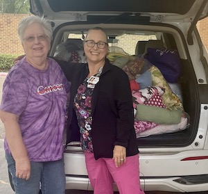 car with breast cancer pillows and 2 volunteers